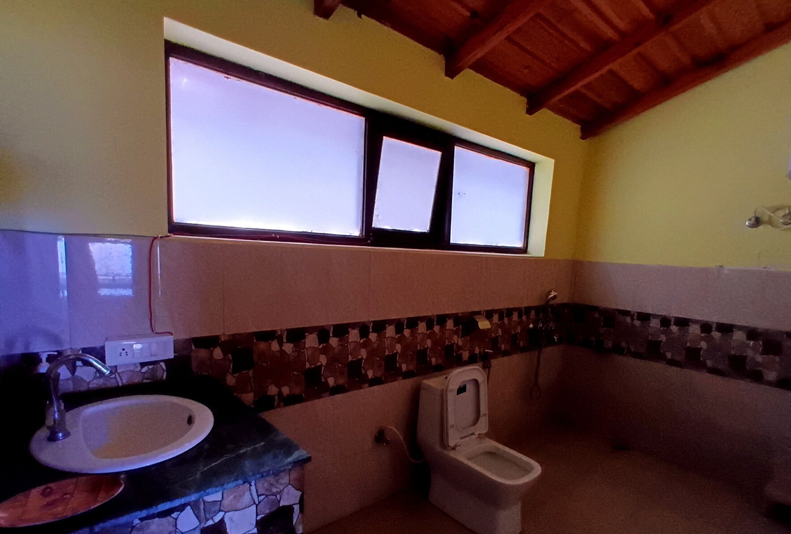 A bathroom with a sink, toilet, and a window above the toilet.