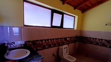 A bathroom with a sink, toilet, and a window above the toilet.