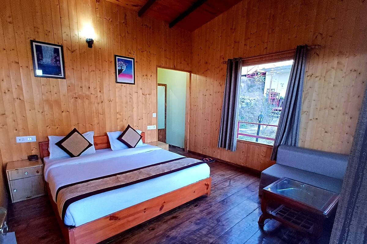 A wooden-paneled room with a bed, bedside table, and a window with curtains.
