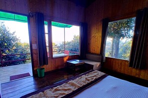 Une pièce de cabane en bois avec une grande fenêtre, une petite table et un banc.