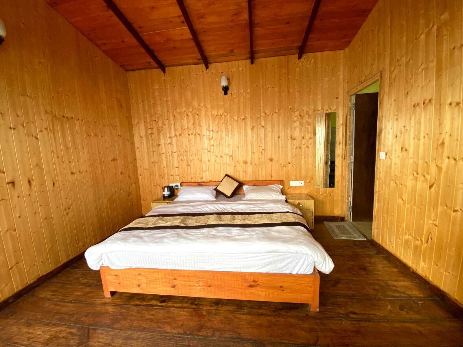 A wooden-paneled room with a bed, a nightstand, and a door.