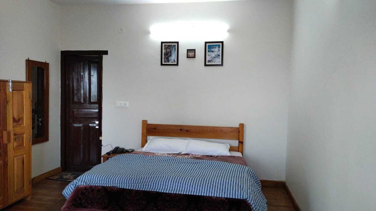 A bedroom with a wooden bed, a wardrobe, and a door. There are two framed pictures on the wall.