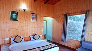 Een slaapkamer in een houten chalet met een bed, een nachtkastje, een raam en een deur.