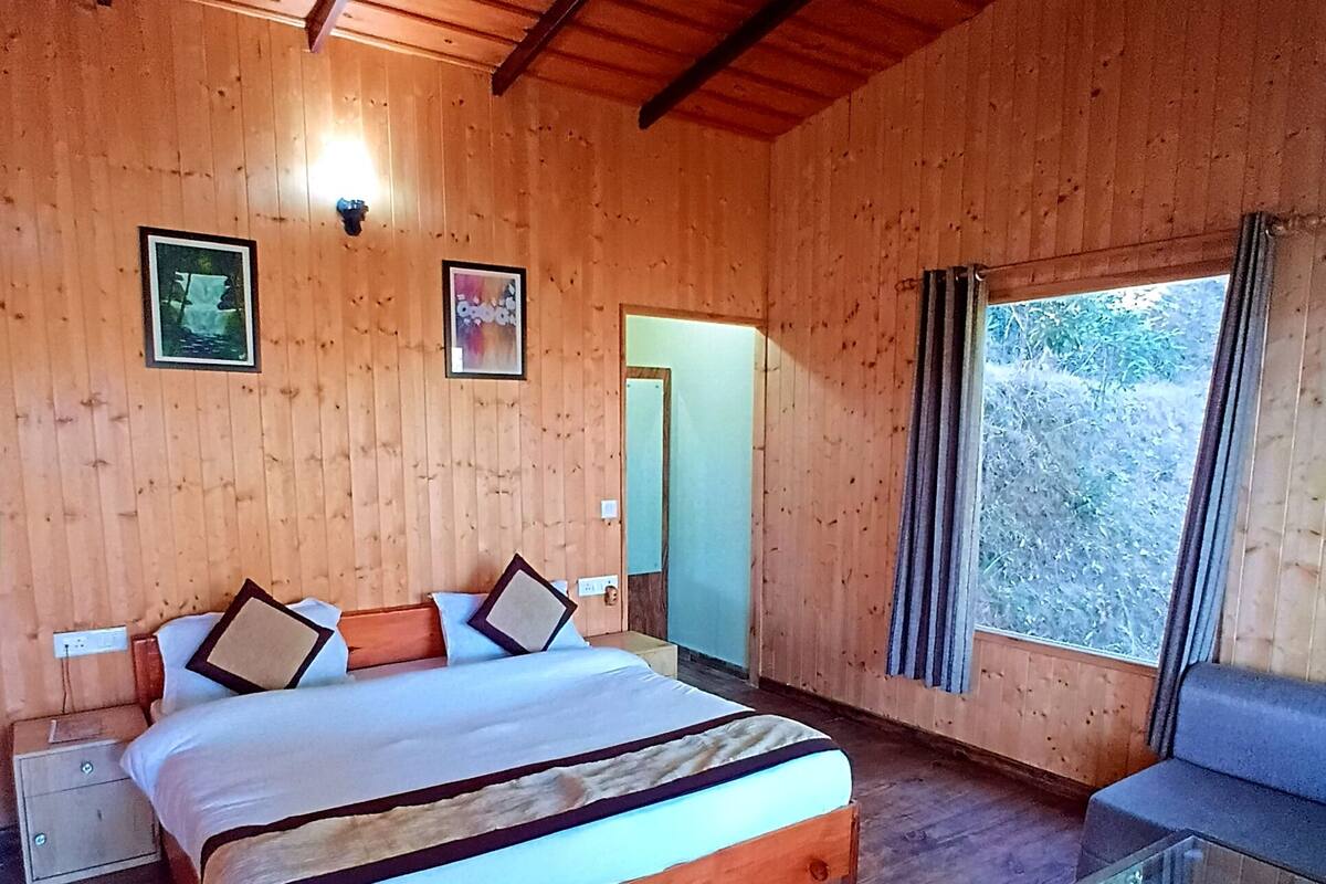 A wooden cabin bedroom with a bed, a nightstand, a window, and a door.
