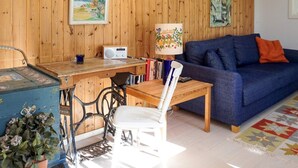 Ett mysigt vardagsrum med en väggpanel av trä, en blå soffa, ett träbord och en stol.