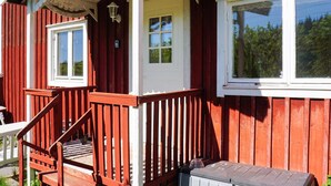 Ett trähus med en veranda, ett fönster och en dörr.