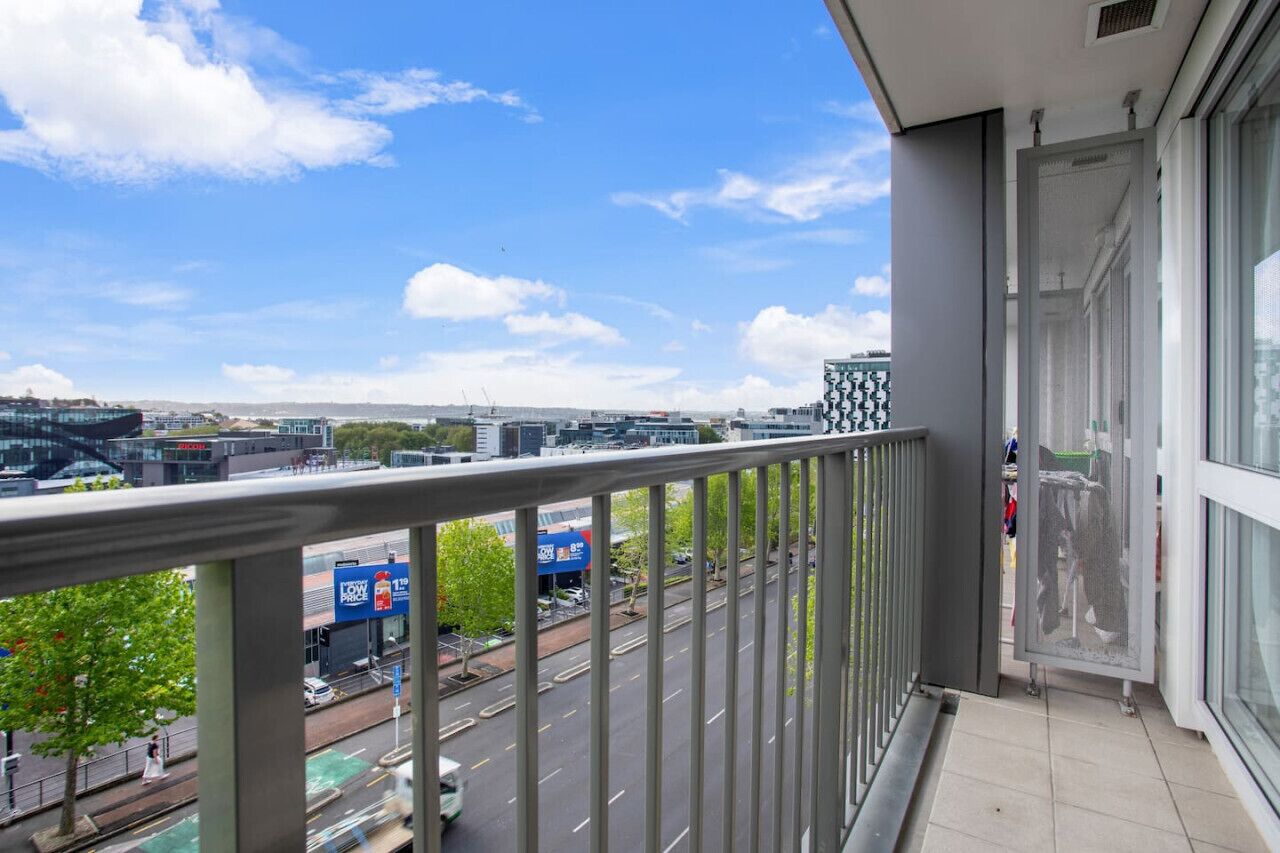 A balcony with a view of a cityscape, including buildings and a road.