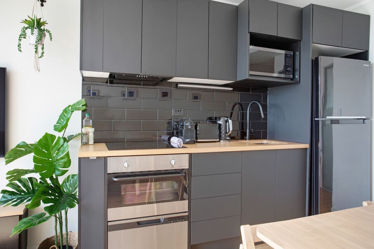 Eine moderne Küche mit grauen Schränken, einer Mikrowelle, einer Kaffeemaschine und einem Kühlschrank.