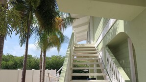 A white staircase leading to a covered outdoor area with a white fence and palm trees. - Waterfront House with Boat Dock (Tavernier)
