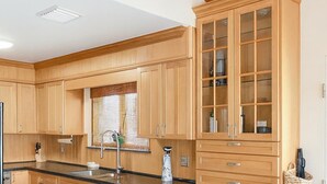 A kitchen with wooden cabinets, a black countertop, and two bar stools. - Waterfront House with Boat Dock (Tavernier)