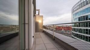 Un bâtiment moderne doté d’une façade en verre, d’une clôture métallique et offrant une vue dégagée sur le paysage urbain en arrière-plan.