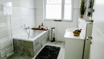 Une salle de bain moderne avec une baignoire, un lavabo et une fenêtre.