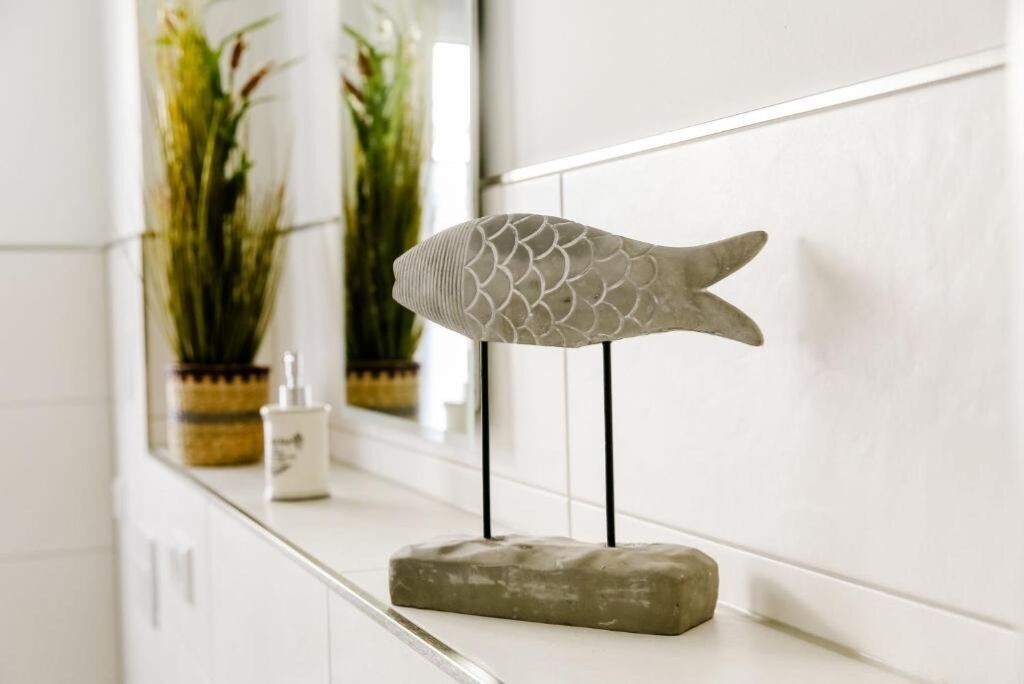 A fish-shaped sculpture on a white tiled wall in a bathroom.