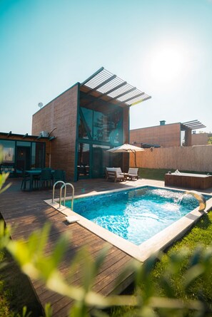 A modern outdoor pool area with a wooden deck, a glass-enclosed patio, and a pergola providing shade. - Stay in Sapanca (Sapanca)
