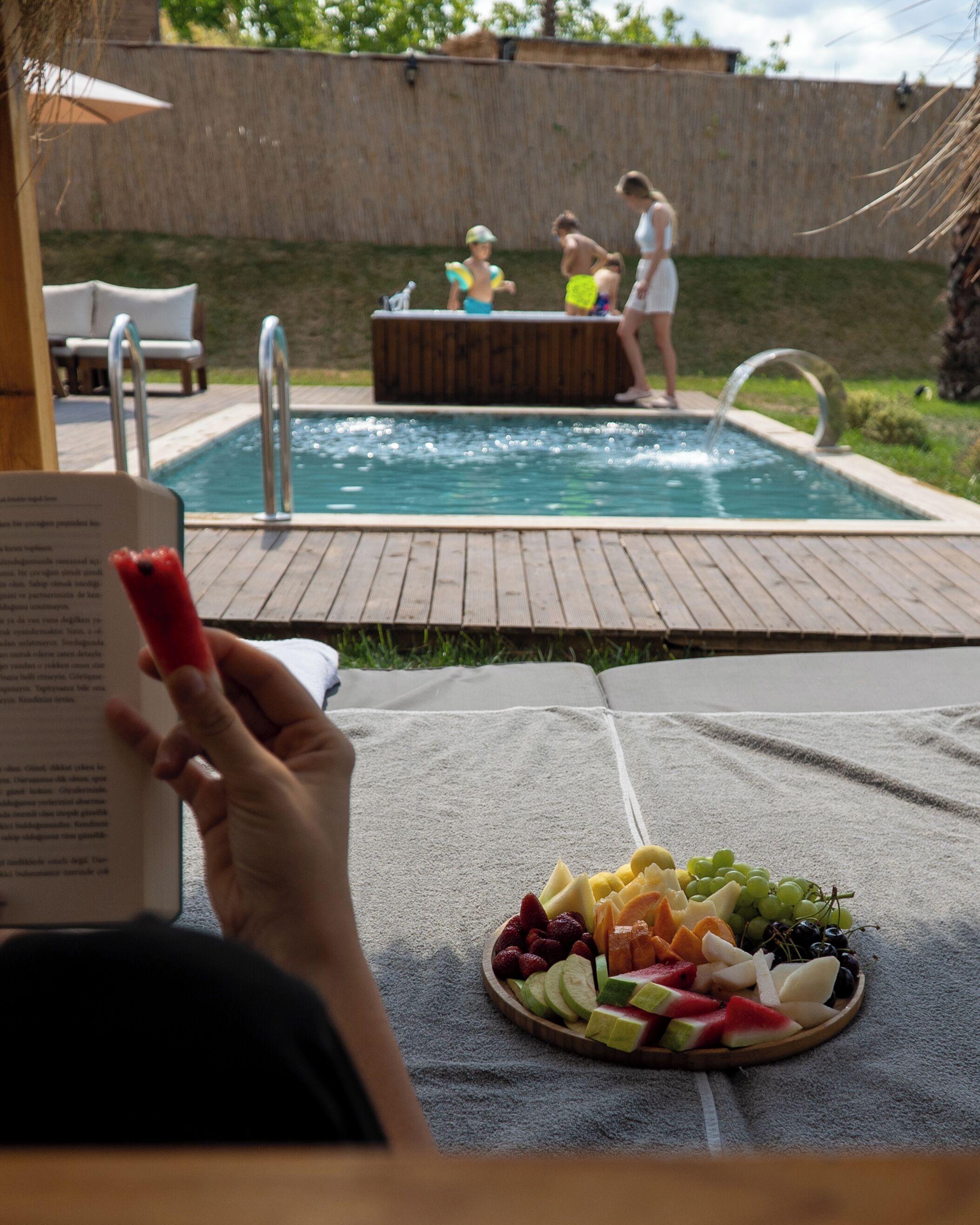 Un espace aménagé au bord de la piscine, comprenant un jacuzzi, une serviette et une assiette de fruits.