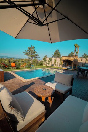 A poolside area with lounge chairs, a wooden deck, and a thatched-roof structure. - Stay in Sapanca (Sapanca)