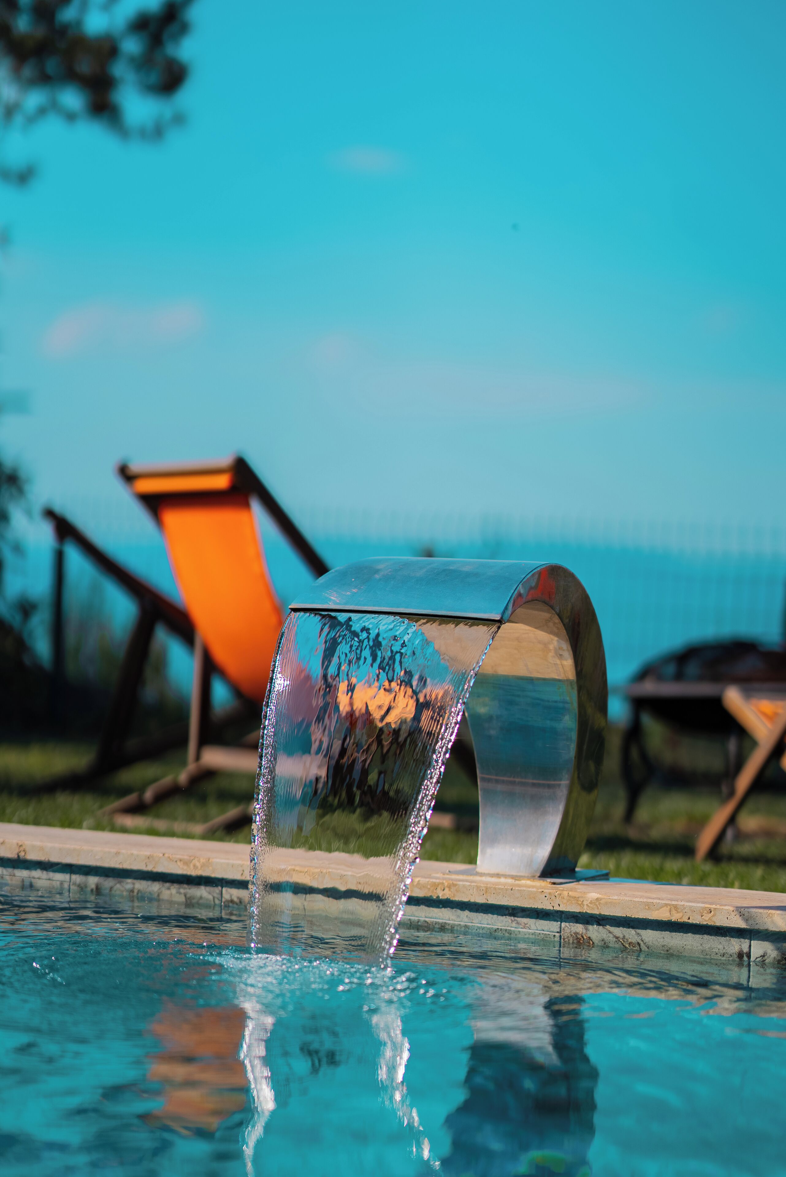 Una piscina con una fuente de agua y una silla al fondo.