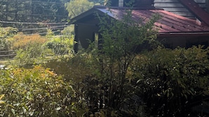 Eine Hütte mit rotem Dach, umgeben von dichtem Wald und blauem Himmel.