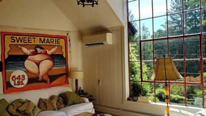 Ein gemütliches Zimmer mit einem großen Fenster, einem Deckenventilator und einem Plakat von 'Sweet Marie'.