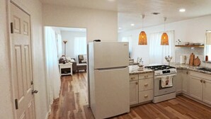 A kitchen with a refrigerator, stove, and hanging lights. - University Casa Bonita (Tucson)