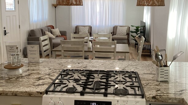 A modern kitchen with a gas stove, a digital clock, and a welcome sign. - University Casa Bonita (Tucson)