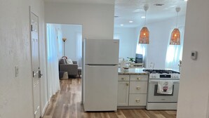A modern kitchen with a refrigerator, stove, and dining area. - University Casa Bonita (Tucson)