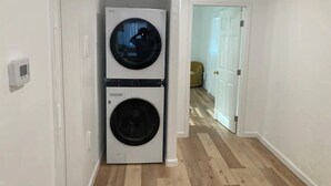 A laundry room with two stacked washing machines and a door leading to another room. - University Casa Bonita (Tucson)