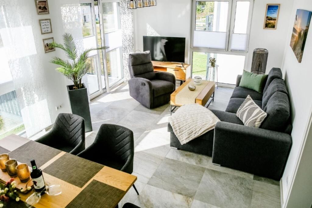 A modern living room with a sofa, chairs, a coffee table, and a TV.