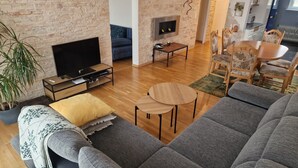 Ein Wohnzimmer mit Backsteinwand, Flachbildfernseher, Sofa, Couchtisch und Kamin.