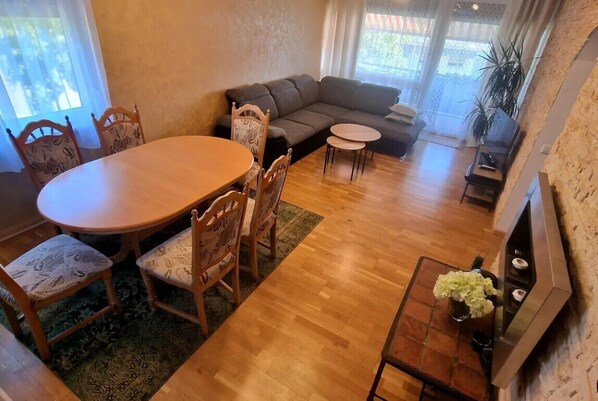 Un salon chaleureux avec une table à manger en bois, des chaises, un canapé et un téléviseur.