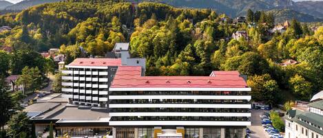 A hotel with a red roof, multiple floors, and a courtyard with outdoor seating.