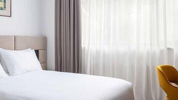 Een hotelkamer met een bed, een stoel en dunne gordijnen.
