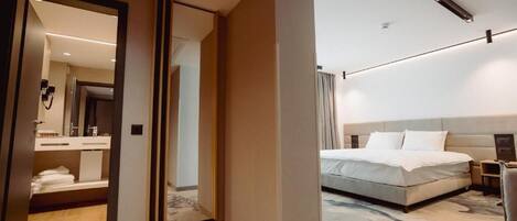 Una habitación de hotel moderna con una cama grande, un baño independiente con espejo y un vestidor.