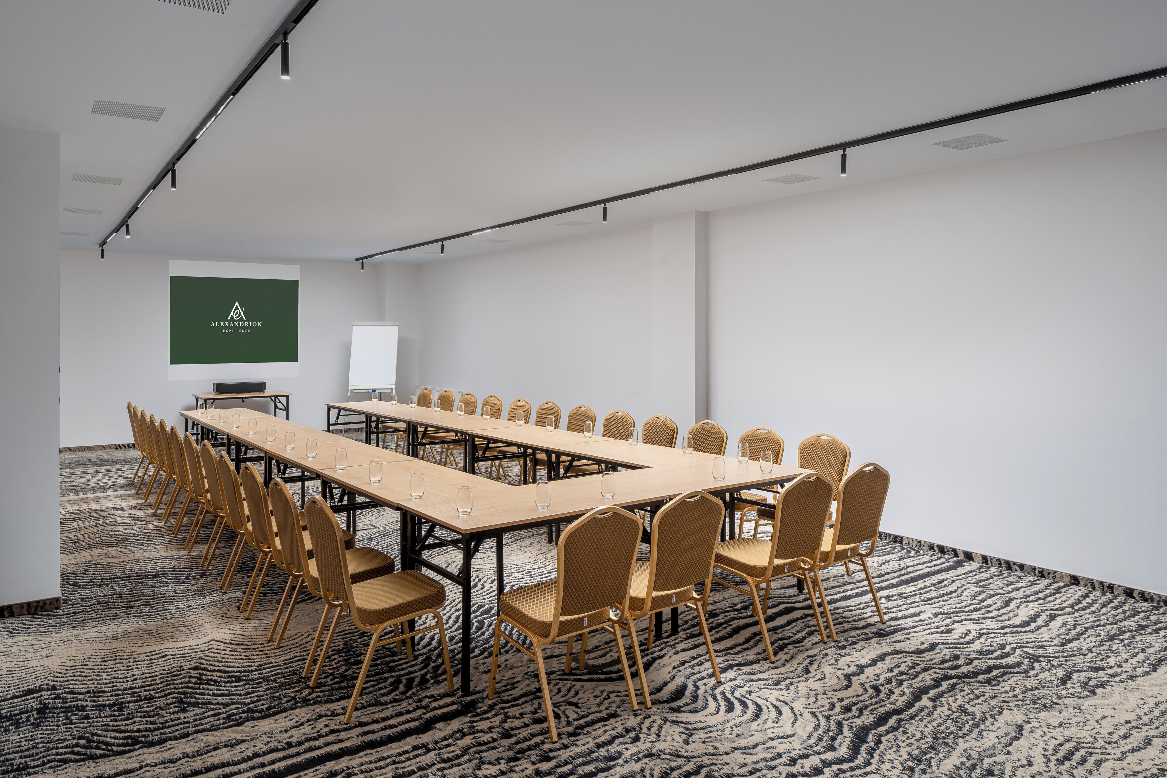A conference room with a long table and chairs, a projector screen, and a carpeted floor.