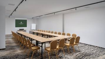 A conference room with a long table and chairs, a projector screen, and a carpeted floor.