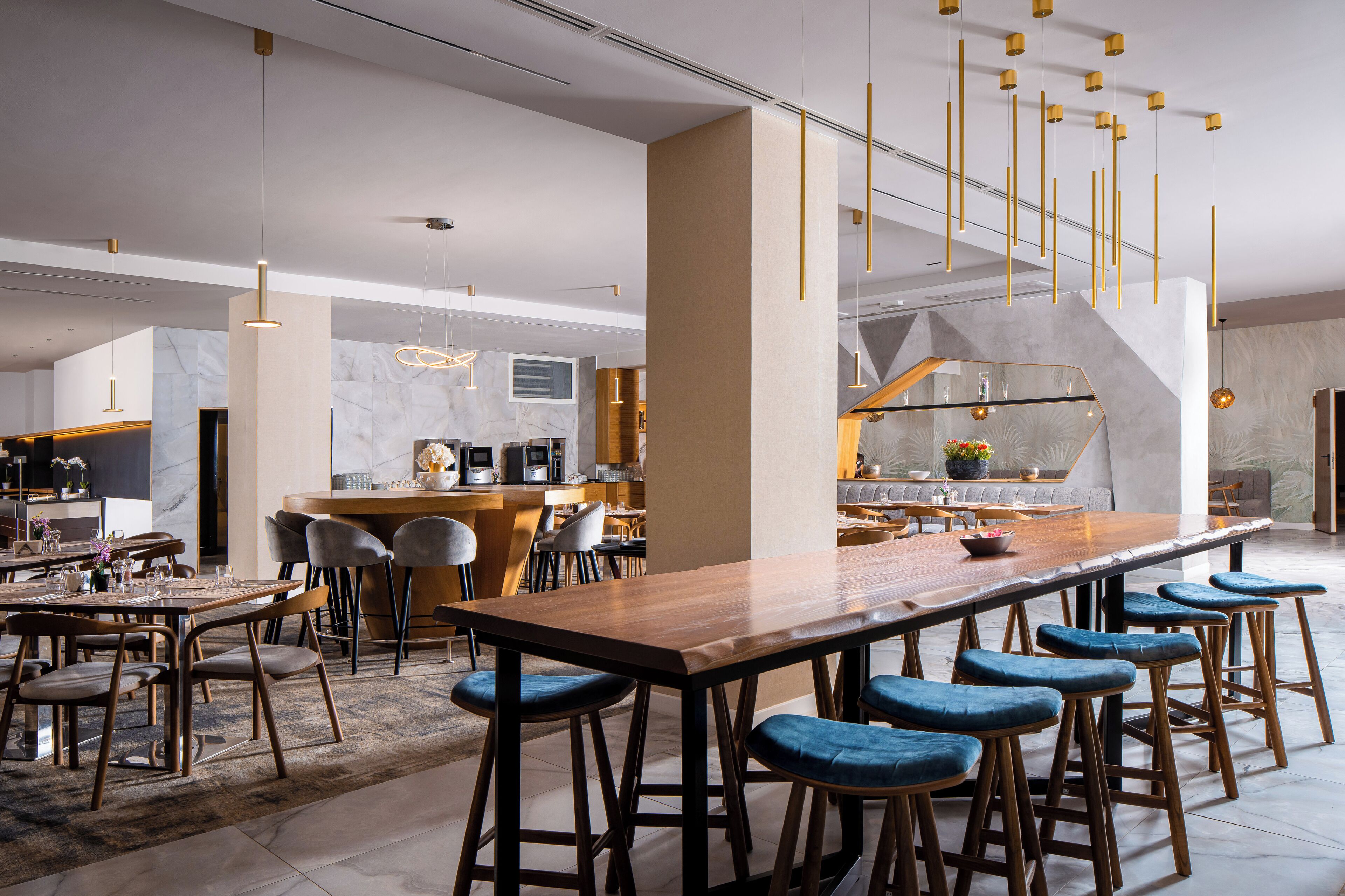 A modern kitchen with a marble backsplash, a wooden bar counter, and blue bar stools.