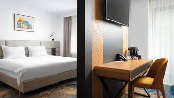 Habitación de hotel con cama, escritorio con silla, televisión de pantalla plana y un cuadro en la pared.