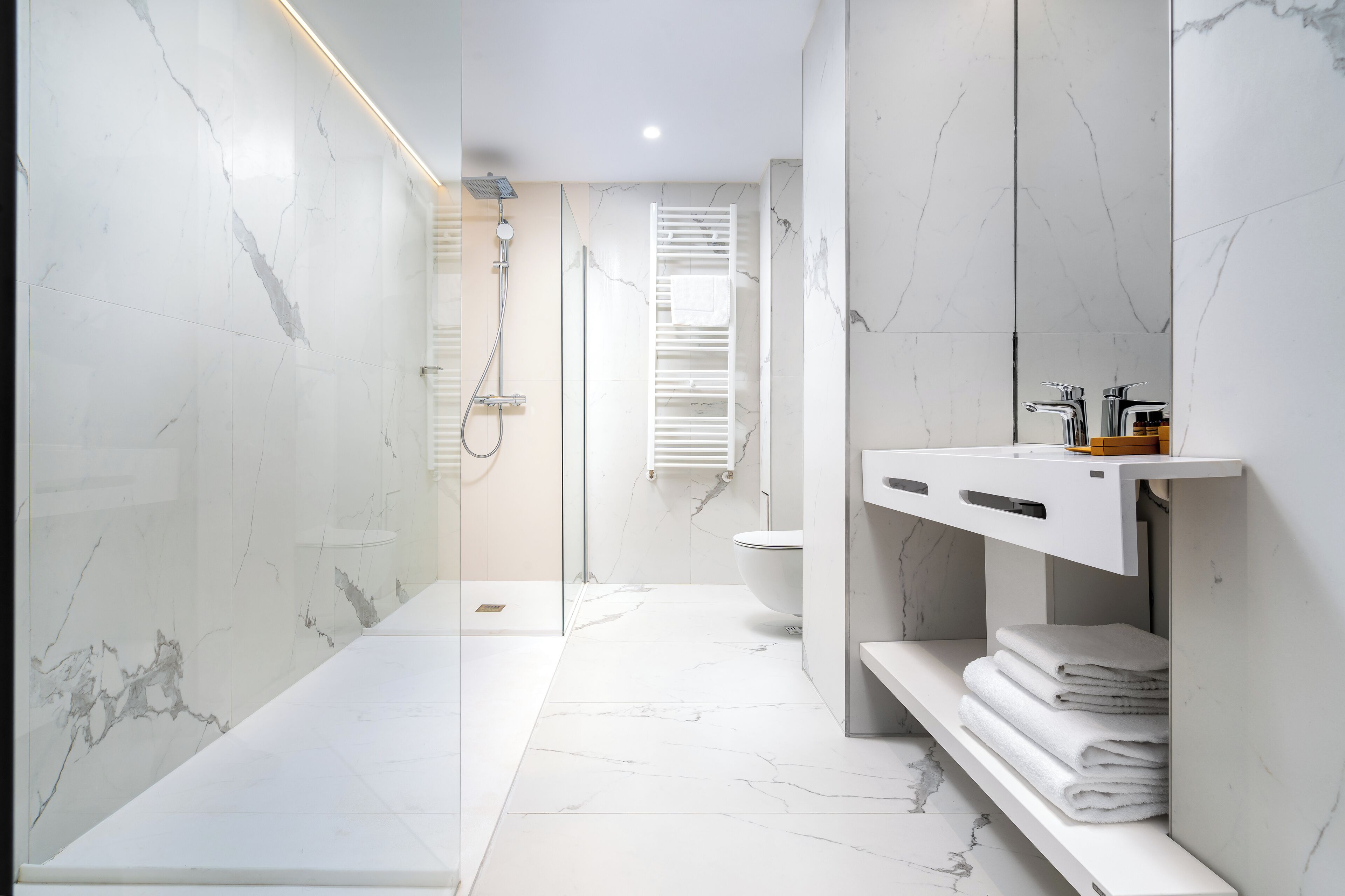 A modern bathroom with a glass-enclosed shower, a white sink, and a toilet.