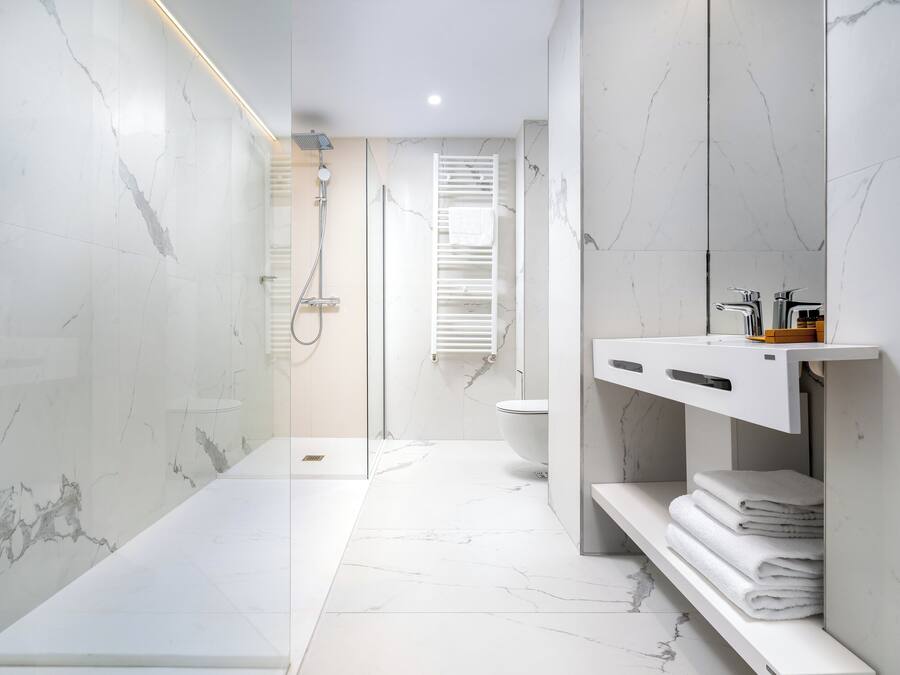 A modern bathroom with a glass-enclosed shower, a white sink, and a toilet.