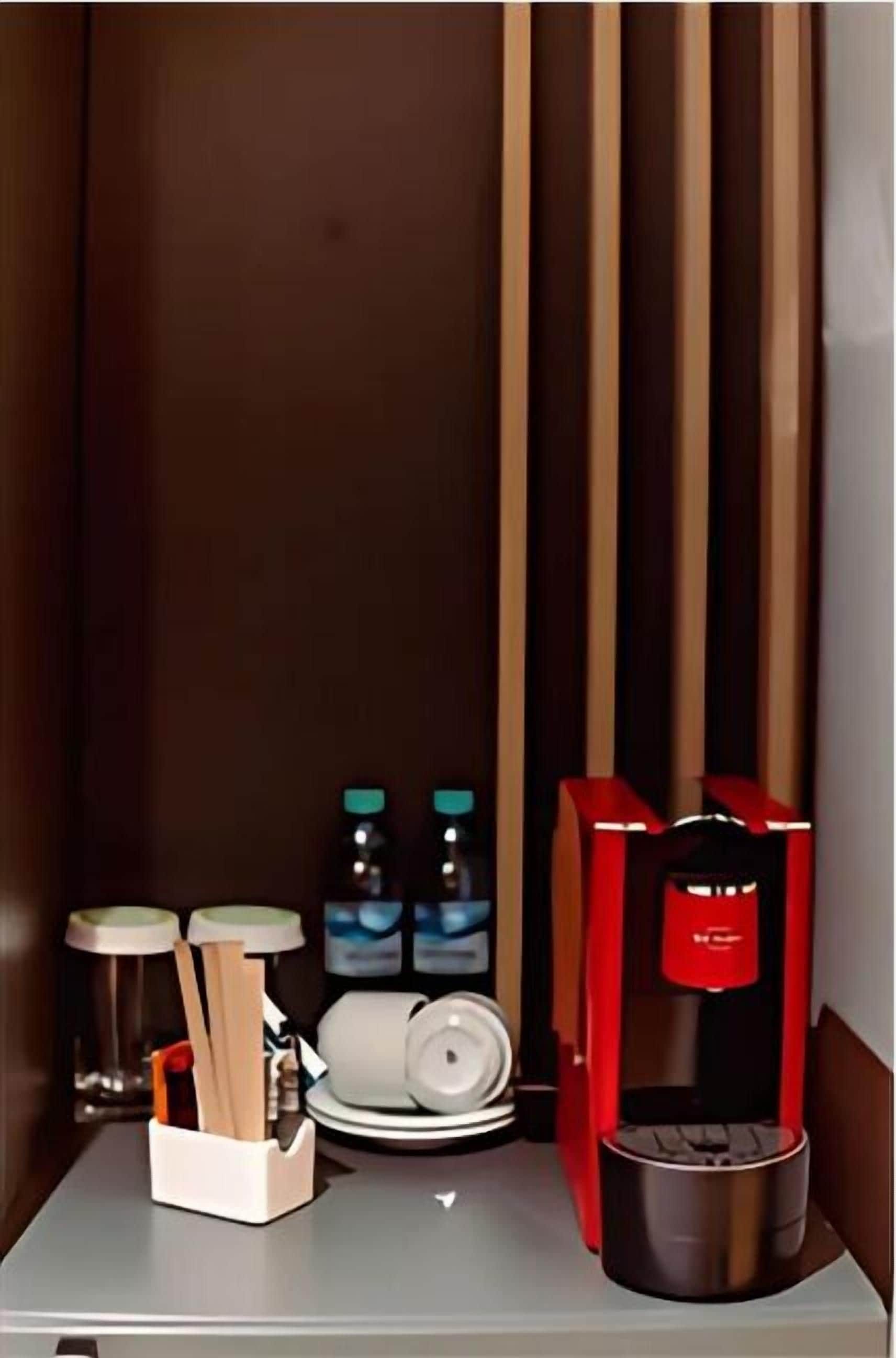 A compact room with a coffee machine, a scale, and a container with utensils.