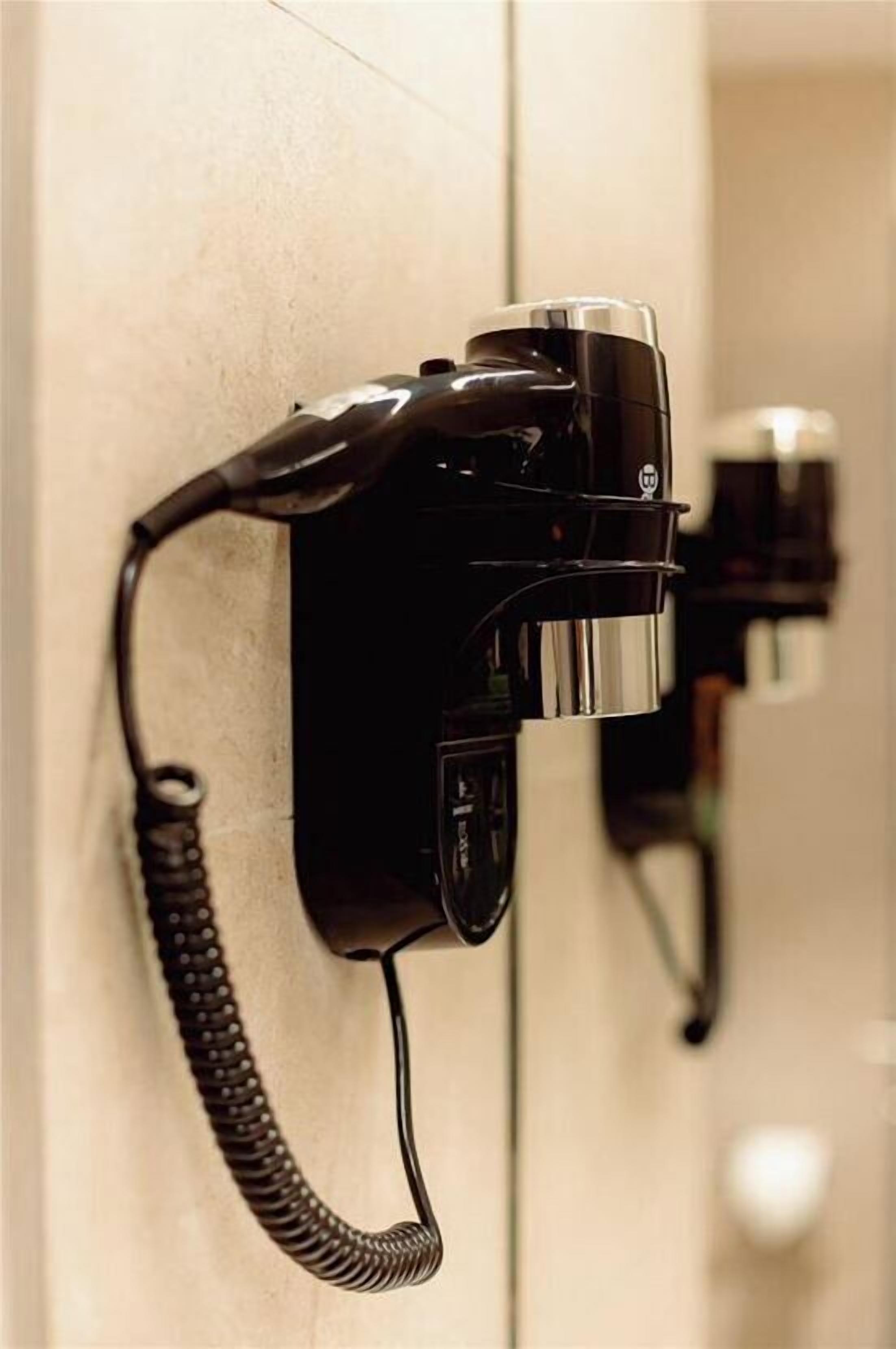 A black telephone mounted on a wall with a coiled cord.