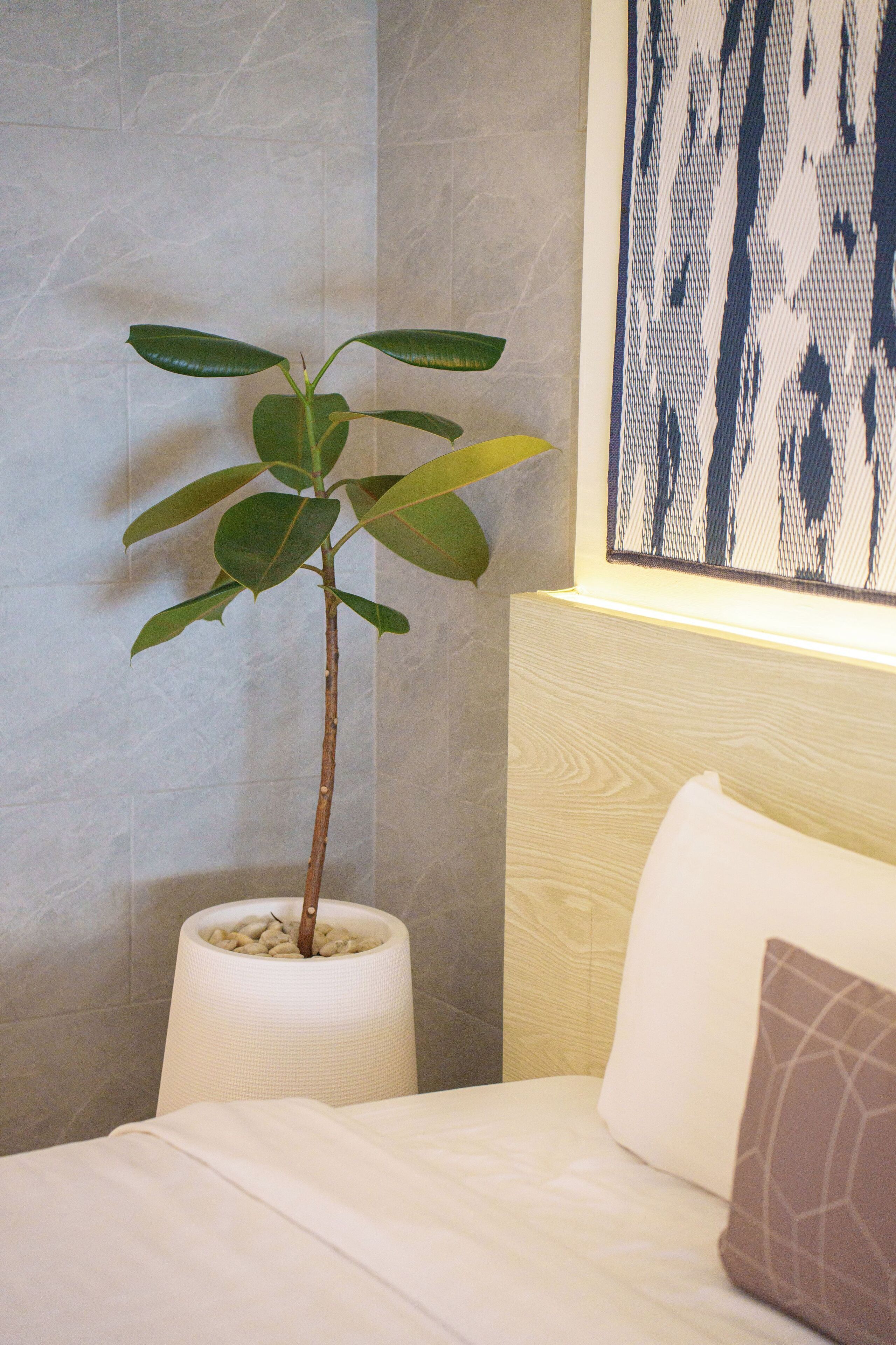 Une chambre d’hôtel avec un lit, une table de chevet ornée d’une plante en pot et une œuvre d’art accrochée au mur.