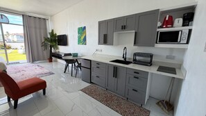 A modern kitchen with grey cabinets, a white countertop, and a built-in microwave. - PÀRIS Villas Tropical Suite (Gros Islet)