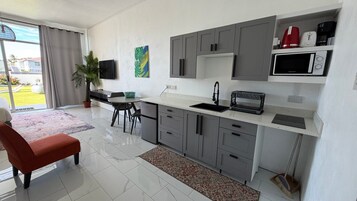 A modern kitchen with grey cabinets, a white countertop, and a built-in microwave.