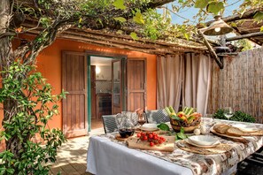 An outdoor dining area with a table set for two, surrounded by greenery and a rustic building. - Villa Sorrentina With Panoramic Terrace (Massa Lubrense)