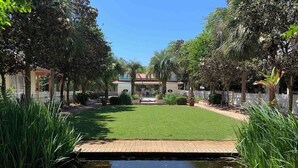 A well-maintained garden with a central lawn, a small pond, and a white fence surrounding the area. - Corner Castle by Southern Vacation Rentals (Destin)