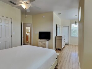 A bedroom with a bed, a TV, a dresser, and a ceiling fan. - Corner Castle by Southern Vacation Rentals (Destin)