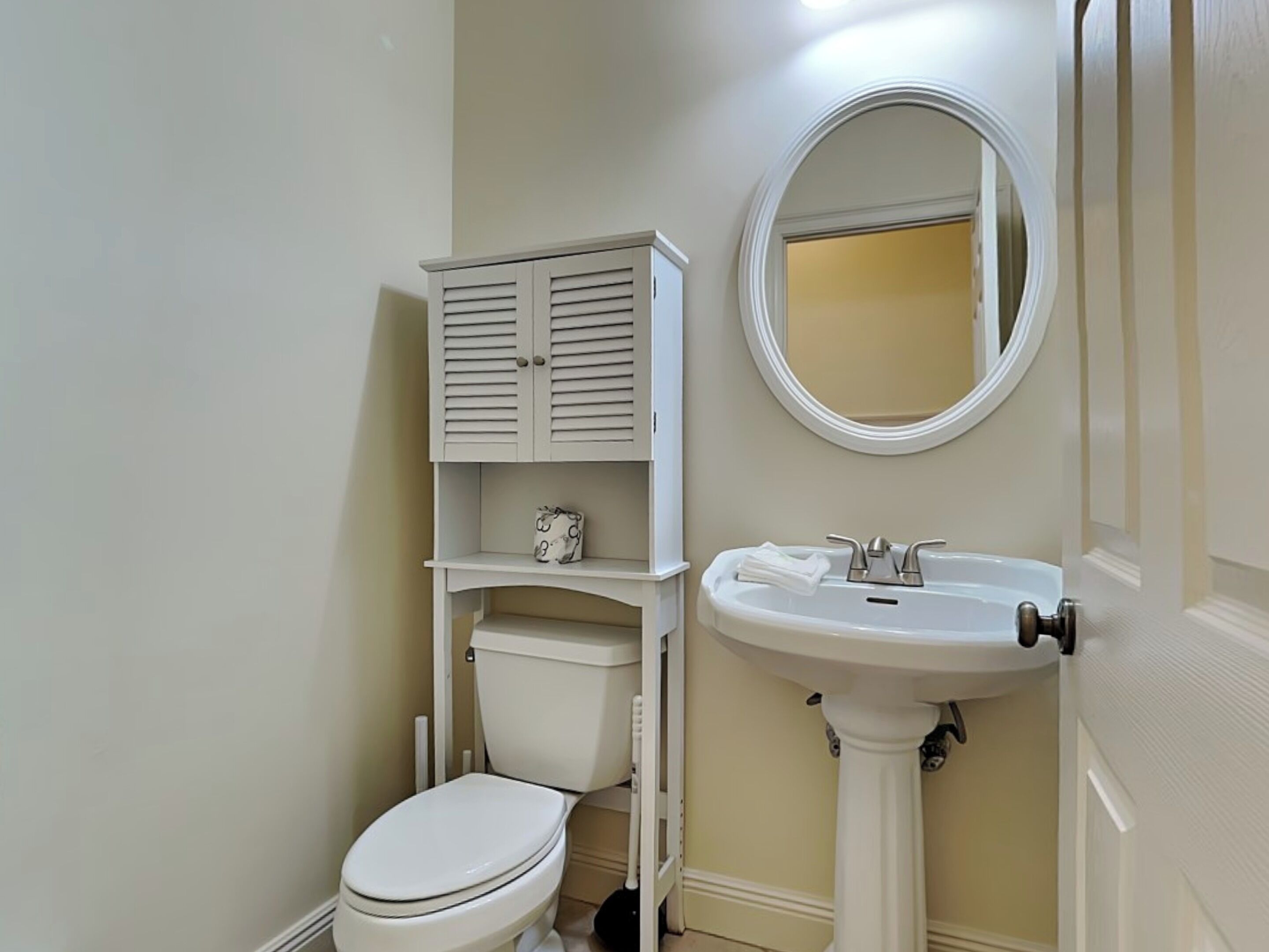 Une salle de bain comprenant des toilettes, un lavabo sur colonne et un meuble avec un miroir au-dessus.