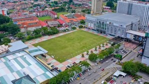 Une vue aérienne d’une ville, avec un grand stade, des bâtiments environnants et une rue animée.