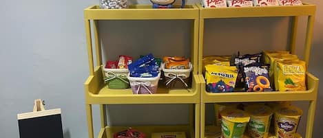 A shelf with various packaged snacks and a small ceramic mug.